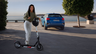 Junge Frau vor der Abfahrt mit ihrem Audi electric kick scooter